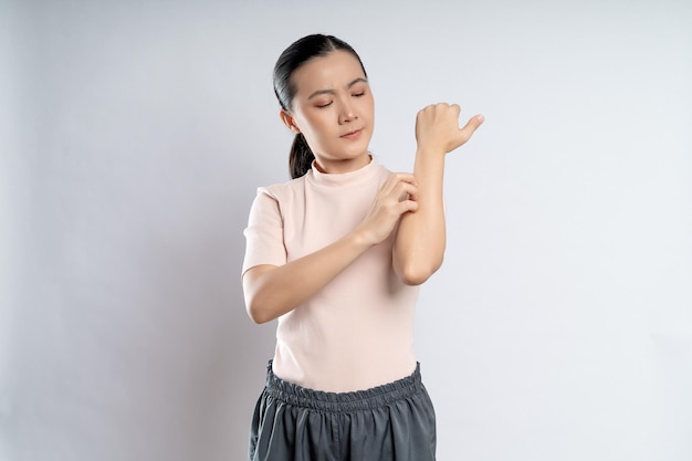 Asian woman was sick with irritate itching her skin standing\
isolated on white background