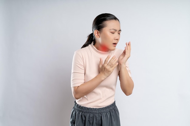 사진 아시아 여성은 목이 아프고 흰색 배경에 격리된 붉은 반점이 있는 목을 만지고 있었다