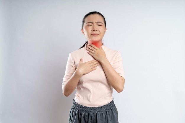 사진 아시아 여성은 목이 아프고 흰색 배경에 격리된 붉은 반점이 있는 목을 만지고 있었다