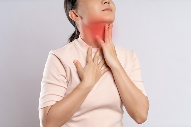 写真 アジアの女性は喉の痛みと白い背景で隔離赤い斑点立って首に触れると病気だった