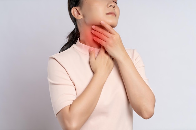 Фото Азиатская женщина болела болью в горле и трогала шею красным пятном, стоящим изолированно на белом фоне