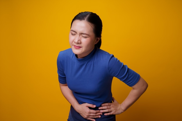 アジアの女性は、腹部を押す手をつないで腹痛に悩まされていました。