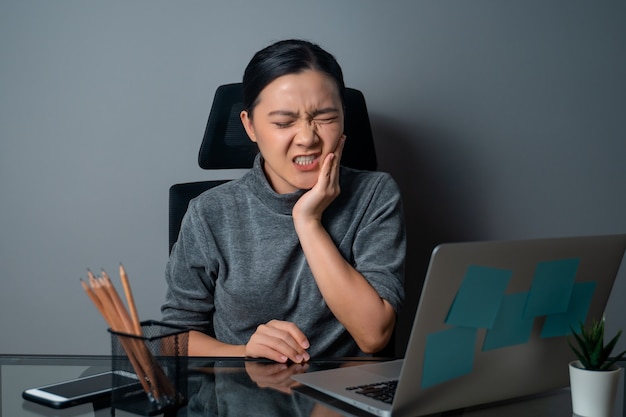 Asian woman was sick with toothache touching her cheek at office 