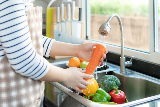 Asian woman washing vegetables in the kitchen