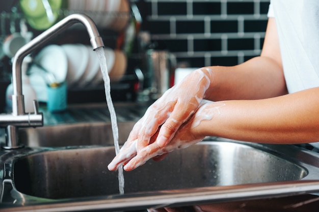 Photo asian woman washing with soap hands thoroughly to corona virus prevention