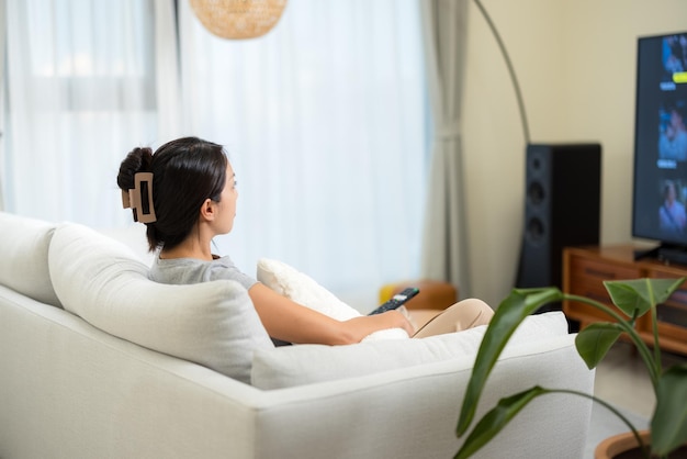 アジアの女性が家でテレビを見ている