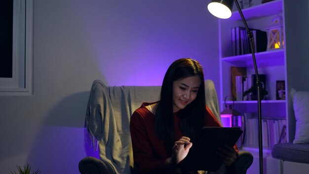 Asian woman watching movie on tablet at the night at home. Relax and recreation lifestyle.