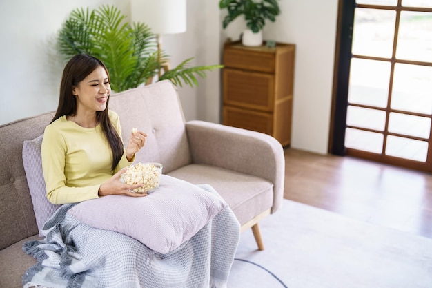 Asian woman Watching smart TV and using remote controller Hand holding television audio remote control at home with the remote control television