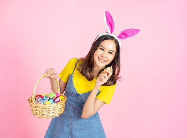 Asian woman wear bunny ear hold easter eggs basket