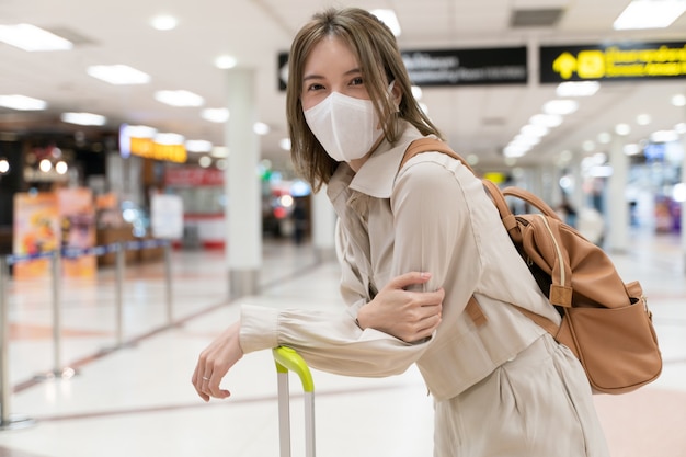 아시아 여자는 공항 터미널에서 여행하는 동안 마스크를 착용