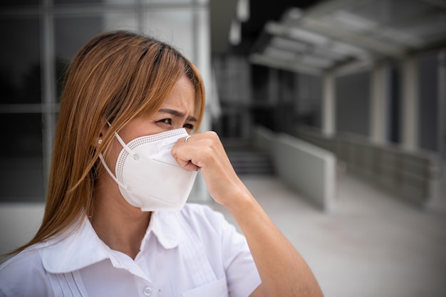 Азиатская женщина носит маску N95 для защиты от пыли 25 вечера концепция экологии Аллергия головная боль воздушная опасность в городе