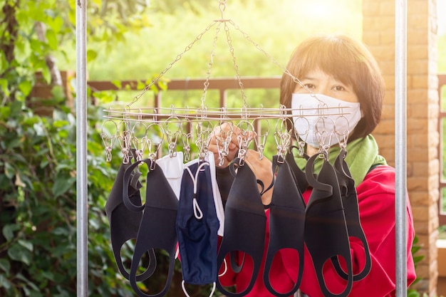 アジアの女性はサージカルマスクを着用し、抗菌とウイルスが新しいフェイスマスクに再利用するために洗顔と乾燥したフェイスマスク