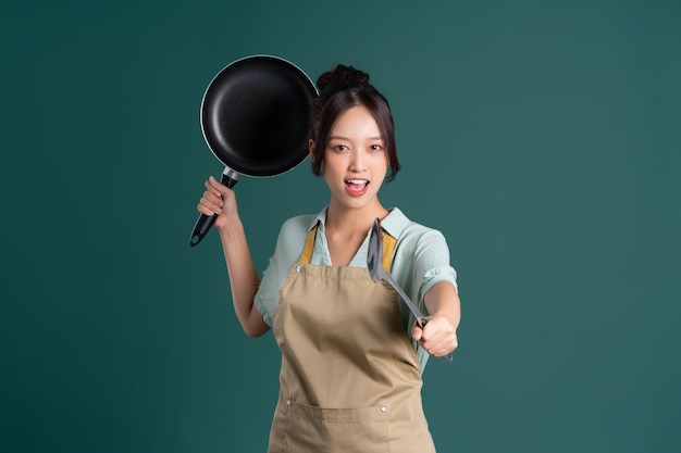 Asian woman wearing apron and holding a pan