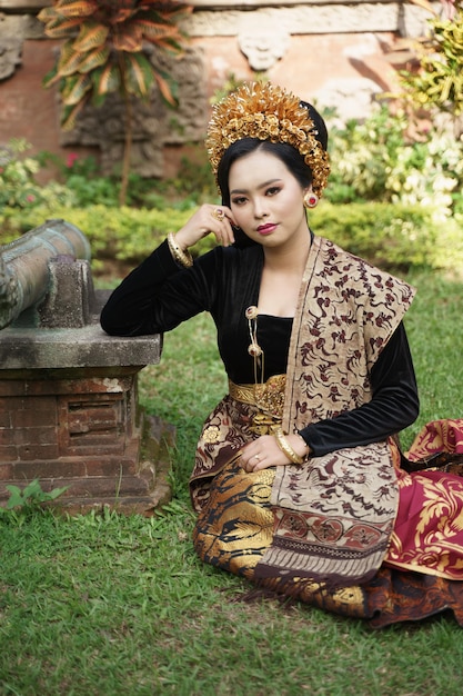 Asian woman wearing balinese kebaya sitting on the grass