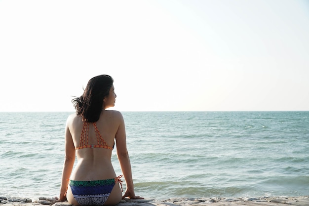 Asian woman wearing bikini on beach yoga