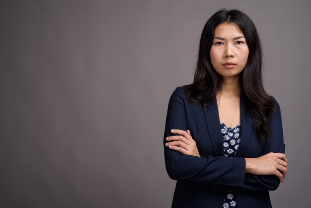 Asian woman wearing blue dress and cardigan sweater against gray space