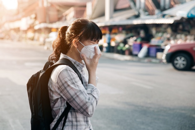 アジアの女性が市内の大気汚染のために咳フェイスマスクを着用