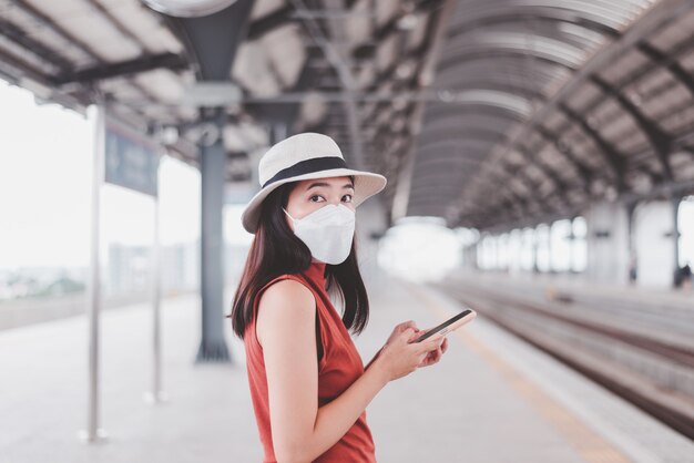 Asian woman wearing face mask and standing at train station,Safety on public transport,New normal during covid-19 pandemic