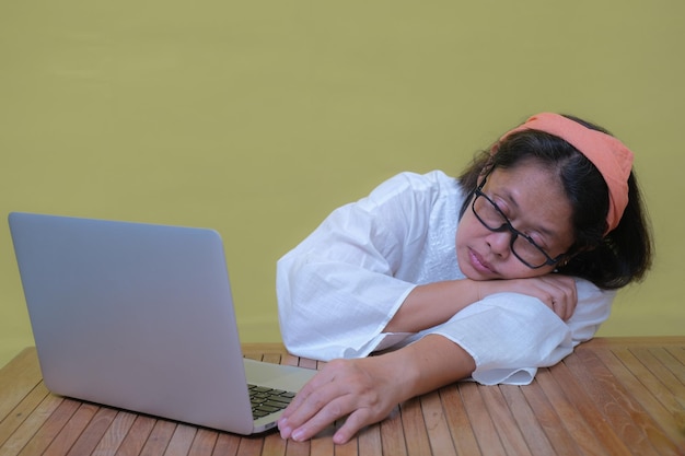 Photo an asian woman wearing glasses falling asleep an open laptop in front of her