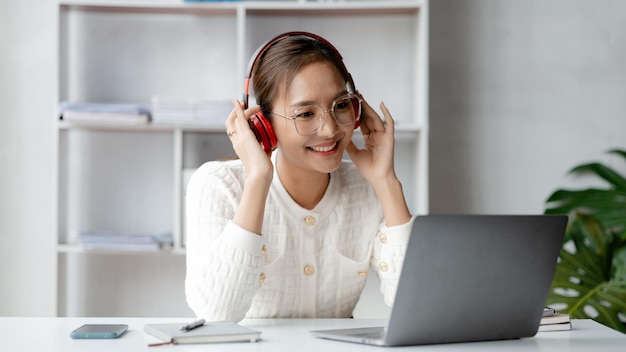 Asian woman wearing headphones to listen to music in her break from work she is in the office of startup company in the marketing department office she takes time to rest before starting work again