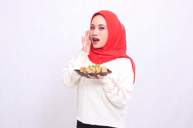 Asian woman wearing hijab gives a whispered announcement and brings a plate containing sushi Japan