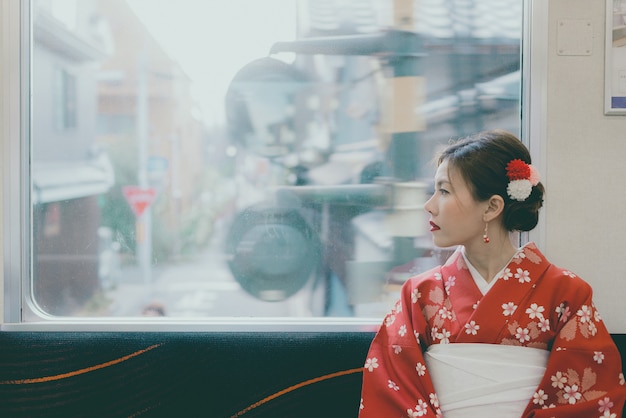 Asian woman wearing kimono traveling by the japan classic train sitting near the window