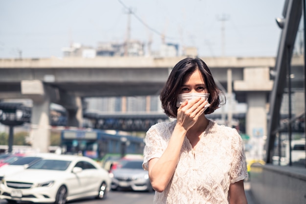 Donna asiatica che indossa una maschera per prevenire il crepuscolo pm 2.5 cattivo inquinamento dell'aria e coronavirus o covid-19