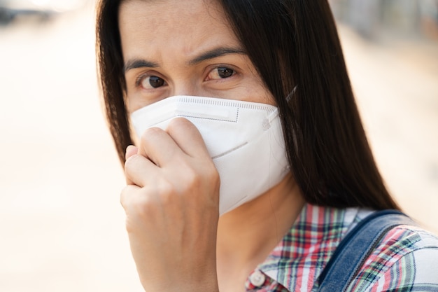 Asian woman wearing N95 face mask to protect pollution PM2.5 and virus. COVID-19 Coronavirus and Air pollution pm2.5 Healthcare and medical concept.