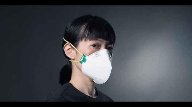 Donna asiatica che indossa una maschera sana n95 per proteggere il coronavirus o covid19 e pm 25 polvere pericolosa