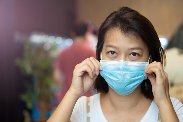 Азиатская женщина в защитной маске на лице, находясь в кафе во время пандемии вируса covid-19.