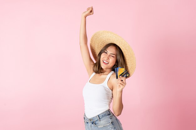 An Asian woman wearing a summer dress, holding a credit card, and raising her hand