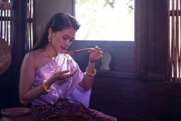 Asian woman wearing Thai dress costume traditional according culture and tradition cooking in the kitchen