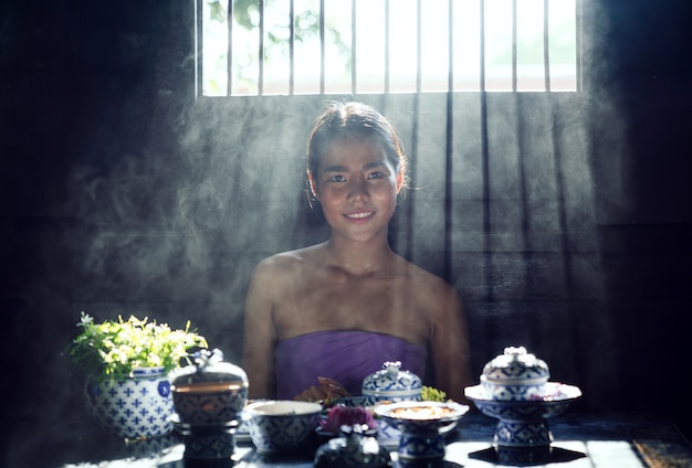 Donna asiatica che porta il costume tailandese del vestito tradizionale secondo la cultura e la tradizione che cucinano nella cucina