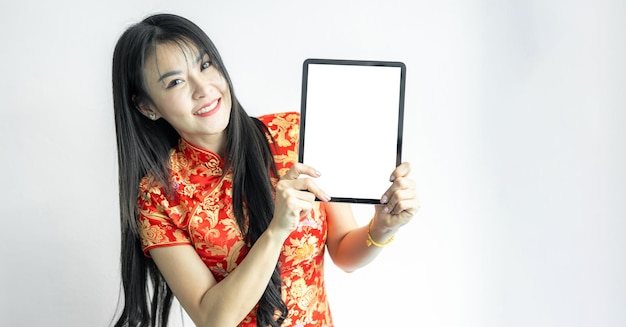 Asian woman wearing traditional cheongsam qipao dress showing presenting digital tablet on white background Chinese new year shopping Shopping online Chinese woman in traditional dress