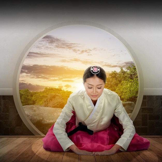 Asian woman wearing a traditional Korean national costume Hanbok sitting with a garden view