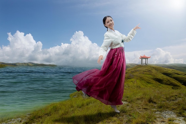 호수 옆에 서있는 한국 전통 의상 한복을 입은 아시아 여성