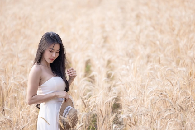 Donna asiatica in un campo di grano ritratto bella donna nel campo di grano sorridente belle donne asiatiche in abito bianco a piedi campi d'orzo d'oro