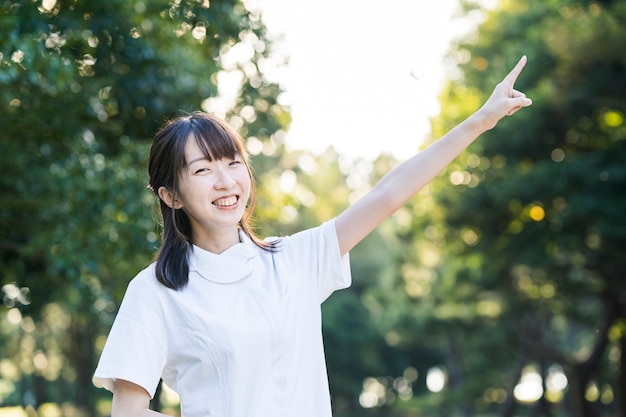 Asian woman in a white coat doing a pointing pose