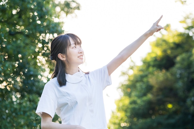 Asian woman in a white coat doing a pointing pose