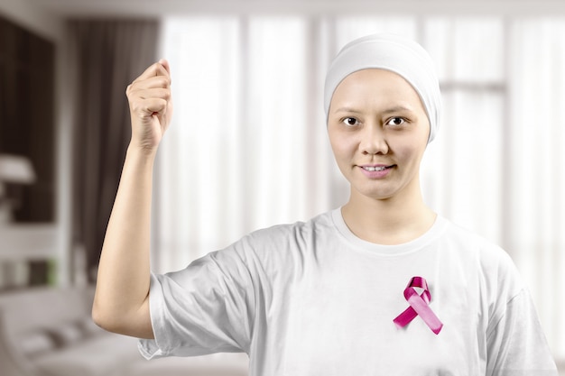 Foto donna asiatica in una camicia bianca con un nastro rosa sulla casa