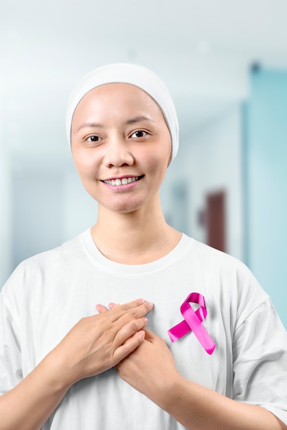 Asian woman in a white shirt with a pink ribbon in the hospital