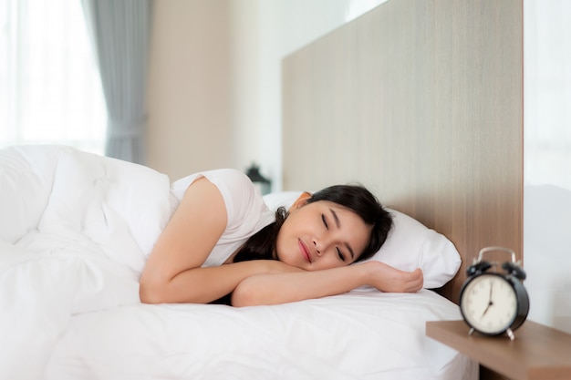 Asian woman with attractive smile enjoy fresh soft bedding linen mattress.