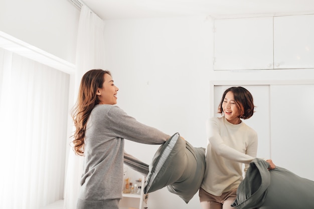 Asian woman with attractive smile while play pillow with friend.