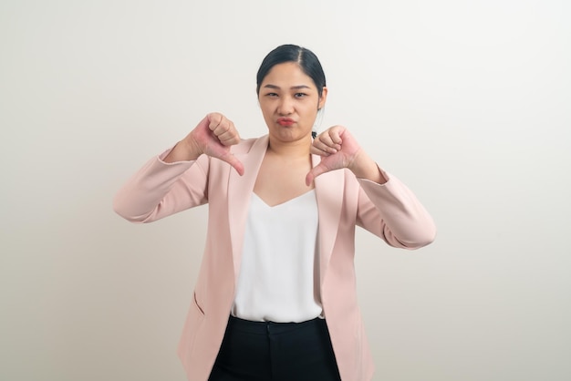 Asian woman with bad mood and bad hand sign on white background