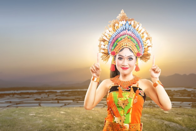Азиатская женщина в костюме балийского традиционного танца, указывая на что-то на открытом воздухе