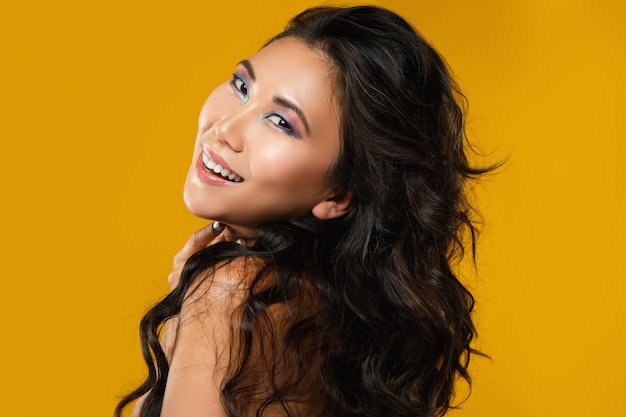 Asian woman with a beautiful curly hair and make-up on yellow