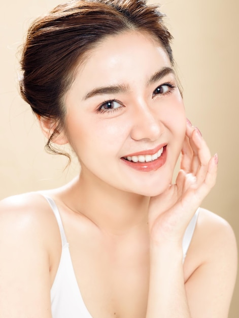 Азиатская женщина с красивым лицом и свежей гладкой кожей. Симпатичная женская модель с естественным макияжем и блестящими глазами позирует на белом изолированном фоне.