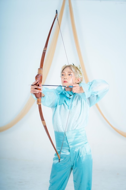 An Asian woman with blonde hair holding an arrow while wearing a blue dress