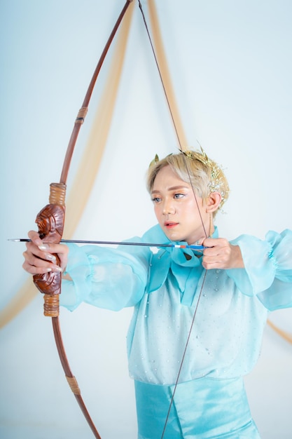 An Asian woman with blonde hair holding an arrow while wearing a blue dress