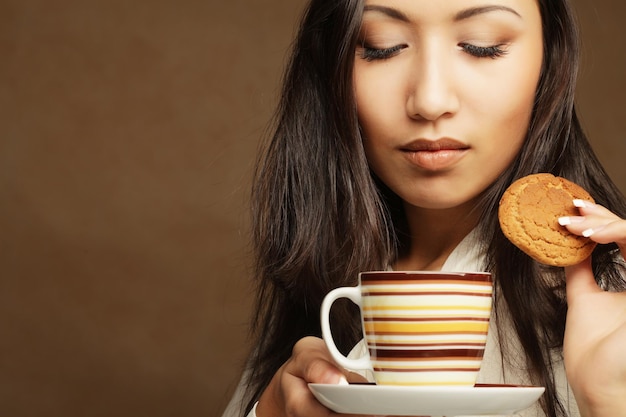 コーヒーとクッキーを持つアジアの女性